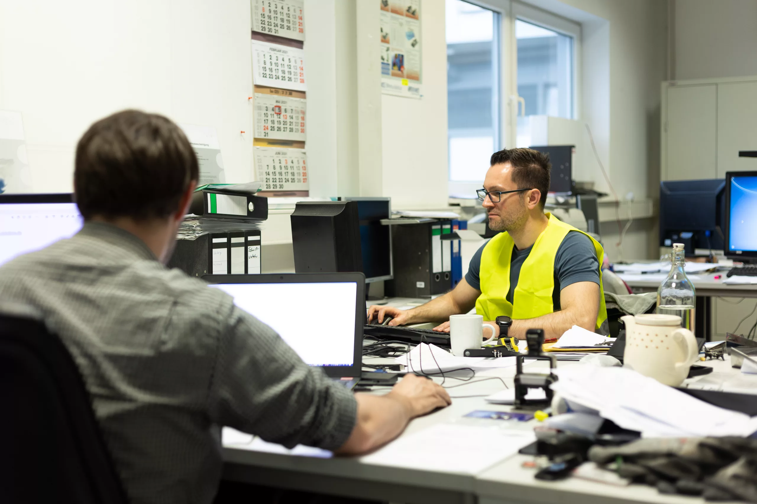 Büroarbeit - Mehrere Mitarbeiter arbeiten am Schreibtisch vor ihren PC's